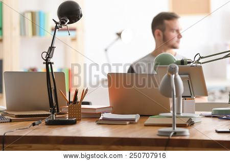 Young people studying indoors. Focus on table with laptops and tablet computer