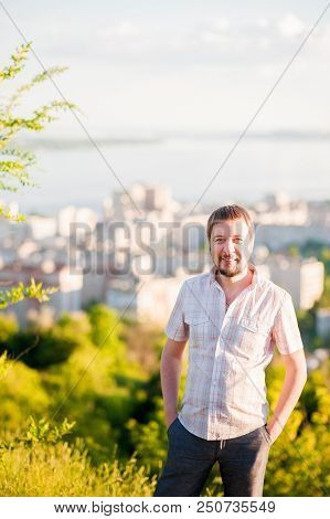 Portrait Of A Man In The Background Of Saratov, Russia, View Of The Houses, The Volga River, The Bri
