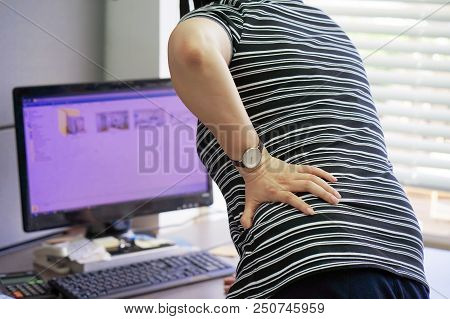 Close-up View Of A Office Worker Woman With Pain In Kidneys. Woman With Back Ache Clasping Her Hand 