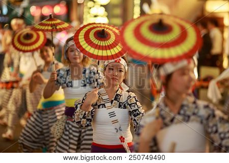 Osaka, Japan - July 23, 2018: Young Woman With Red And Yellow Paper Umbrellas Participate In A Parad