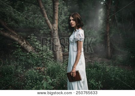 Female victim in white dress holds book in hand