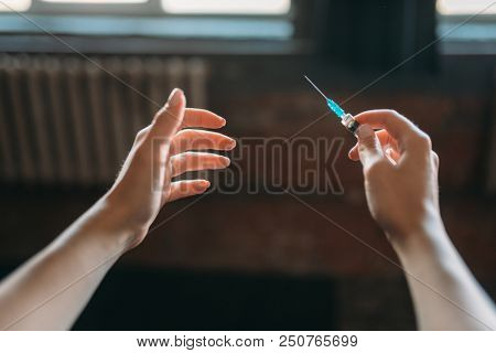 Junkie hands with syringe, drug addiction concept