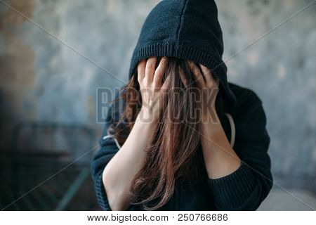 Female in a hoodie holds her head