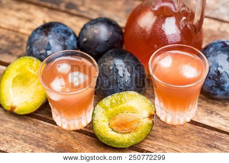 Close Up Plum Liqueur Or Slivovitz, Plum Rakia With Fresh And Tasty Plums In Wooden Bowl On Wooden B
