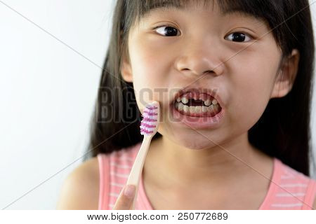 Little Asian Girl Without Front Teeth Holding A Tooth Brush
