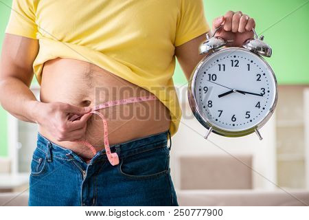 Man measuring body fat with tape measure in time management conc
