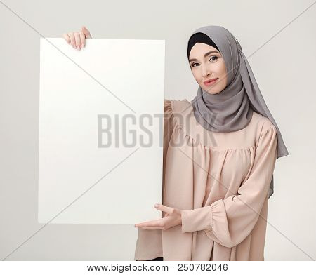 Blank Billboard For Ramadan Greeting. Beautiful Muslim Woman In Hijab Holding White Poster With Copy