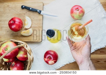 Top View Of Ripe Juicy Apples And Glass Of Cidre Drink On Rustic Wooden Table. Point Of View Of Hand
