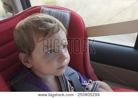 Handsome Attentitive Baby Boy In Child Car Seat. He Is Watching Toons With Tablet On Headrest