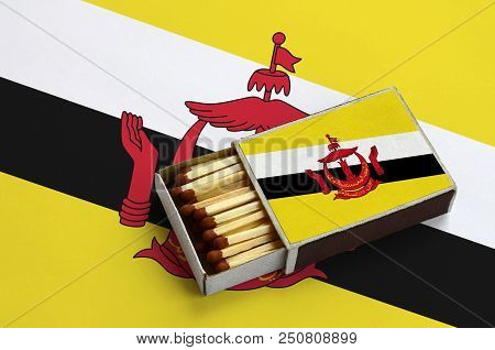 Brunei Darussalam Flag  Is Shown In An Open Matchbox, Which Is Filled With Matches And Lies On A Lar