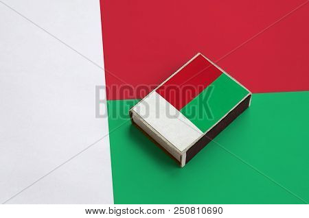Madagascar Flag  Is Pictured On A Matchbox That Lies On A Large Flag.