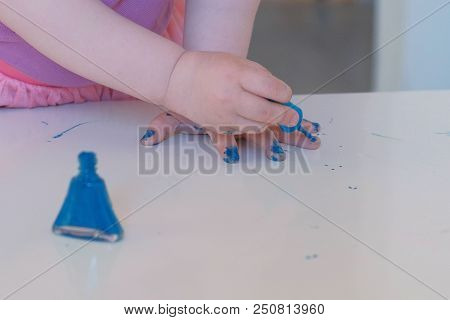 Little Cute Girl Paints Her Nails With Blue Varnish.