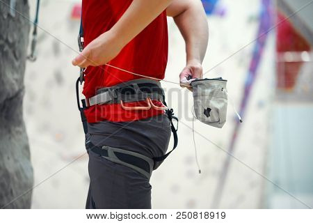 Close-up of male climber with talc bag in gym