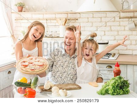 dad with two little daughters preparing pizza in the kitchen