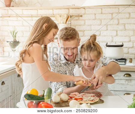 dad with two little daughters preparing pizza in the kitchen