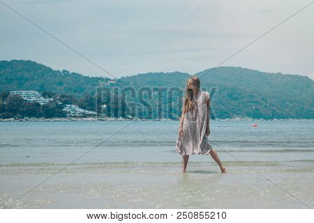 Handsome Girl On The Beach Background. Portrait Of A Woman In White Clothes On The Sea