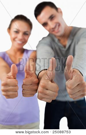 Close up of thumbs up essendo dato da giovane coppia contro uno sfondo bianco