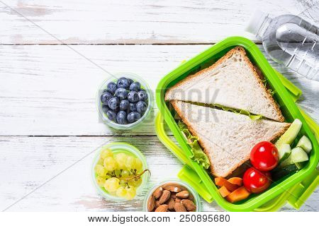 Lunch Box With Sandwich, Vegetables, Water, Yogurt, Nuts And Berries. Healthy Food To Go. Top View W