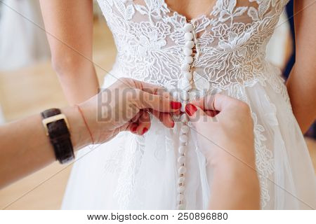 A Beautiful Morning Of The Bride. Dressing The Dress. The Bride Tightens The Corset, Fastens The But