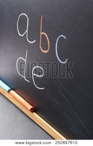 Fragment Of Black Chalkboard With Hand Written Latin Alphabet Multicolored Chalks. Back To School Co