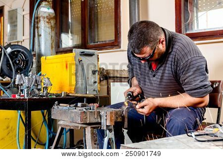 Sculptor Is Using Arc Welding To Assembly Metal Sculpture Barehanded With Protective Spectacles.