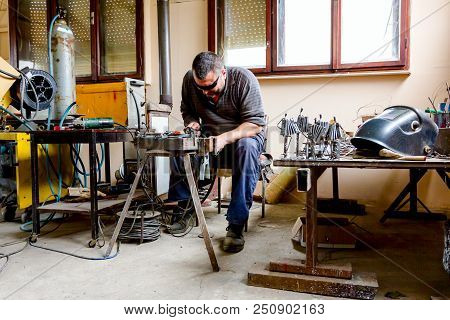 Sculptor Is Using Arc Welding To Assembly Metal Sculpture Barehanded With Protective Spectacles.
