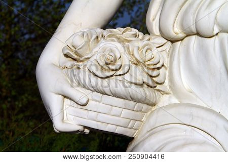Hand Of White Female Marble Statue With Basker Of Rose Flowers In Hand Close Up On Black Background