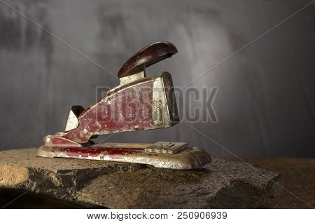 Old Stapler On The Stone And Dark Background