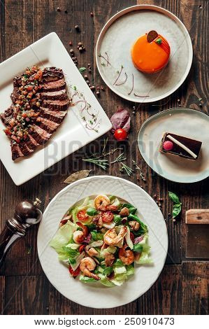 Menu Composition Of Dishes Decorated With Included Seafood Salad, Meat And Cake