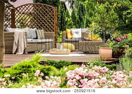 Wooden Terrace With Couch With Pillows, Armchair, Table With Fresh Fruits And Candles On Wicker Foot