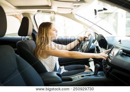 Beautiful Young Woman Using Infotainment On Dashboard Of Car While Driving