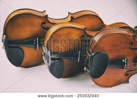 The Classic Old Film Design Background Of Wooden Violin,three Violins Stacked On Board,warm Light To
