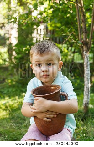 Cute Little Boy Holding A Old Clay Pot. Milk Jug.