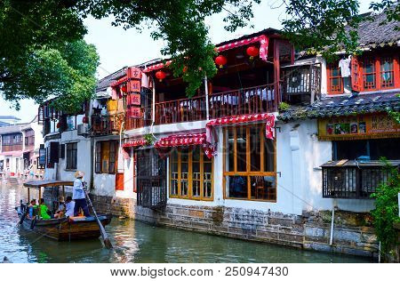 Shanghai, Zhujiajiao, China, July 2015. A Boat With Boatman And Tourists On The Tree-covered Canal I