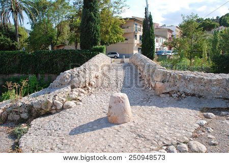 MAJORCA, SPAIN - SEPTEMBER 4, 2017: The Roman bridge across the Torrente de Sant Jordi at Pollenca on the Spanish island of Majorca. The actual origin of the bridge is unconfirmed.