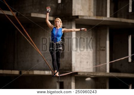 Female Equilibrist Walking With One Arm Raised And Other To The Left On The Slackline On The Backgro