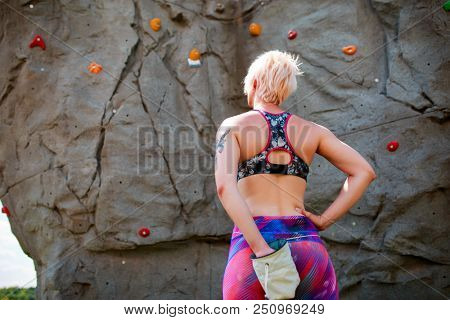 Photo from back of sports girl with bag against rock boulder