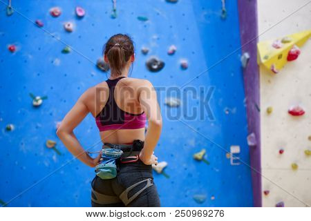Photo of young athlete from back with hands on waist-standing next to wall for rock climbing