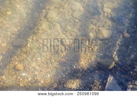 Pebbles On The Beach Pebbles On The Sea Shore And Waves Of Water Illuminated By The Rays Of The Sun