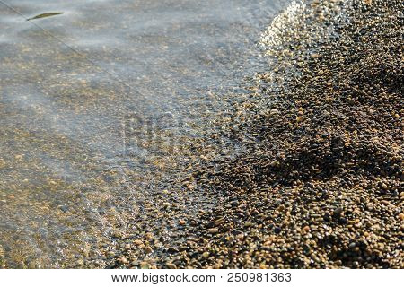 Pebbles On The Beach Pebbles On The Sea Shore And Waves Of Water Illuminated By The Rays Of The Sun