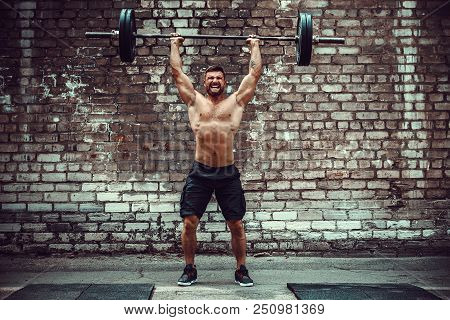 Muscular Fitness Man Doing Deadlift A Barbell Over His Head In Outdoor, Street Gym. Functional Train