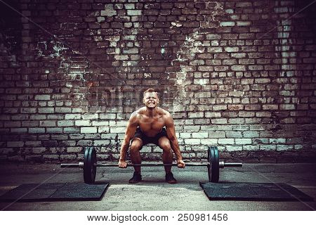 Muscular Fitness Man Doing Deadlift A Barbell Over His Head In Outdoor, Street Gym. Functional Train
