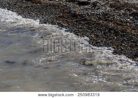 Pebbles On The Beach Pebbles On The Sea Shore And Waves Of Water Illuminated By The Rays Of The Sun