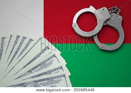 Madagascar Flag  With Handcuffs And A Bundle Of Dollars. The Concept Of Illegal Banking Operations I