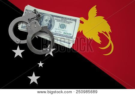 Papua New Guinea Flag  With Handcuffs And A Bundle Of Dollars. The Concept Of Breaking The Law And T