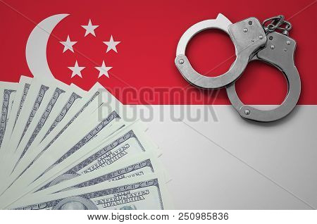 Singapore Flag  With Handcuffs And A Bundle Of Dollars. The Concept Of Illegal Banking Operations In