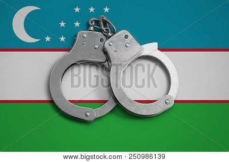 Uzbekistan Flag  And Police Handcuffs. The Concept Of Observance Of The Law In The Country And Prote