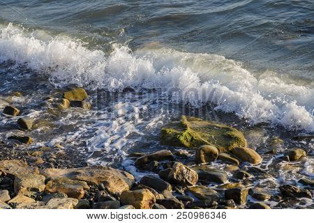 Pebbles On The Beach Pebbles On The Sea Shore And Waves Of Water Illuminated By The Rays Of The Sun