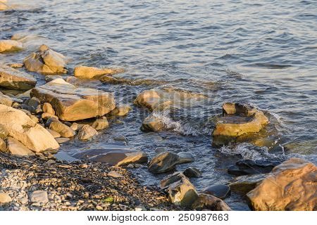 Pebbles On The Beach Pebbles On The Sea Shore And Waves Of Water Illuminated By The Rays Of The Sun