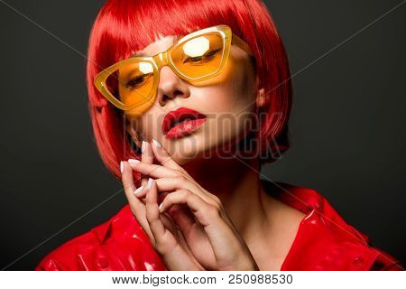 Close-up Portrait Of Stylish Young Woman In Red Latex Jacket And Vintage Yellow Sunglasses Isolated 